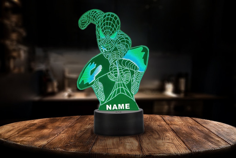 May include: A green and blue 3D printed night light shaped like a superhero with the word "NAME" printed on the base.