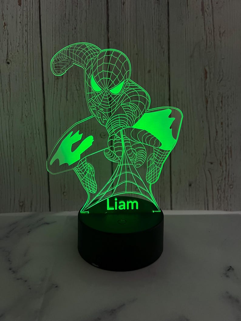 May include: Green 3D printed night light featuring a superhero character with a web design. The name "Liam" is printed below the character.