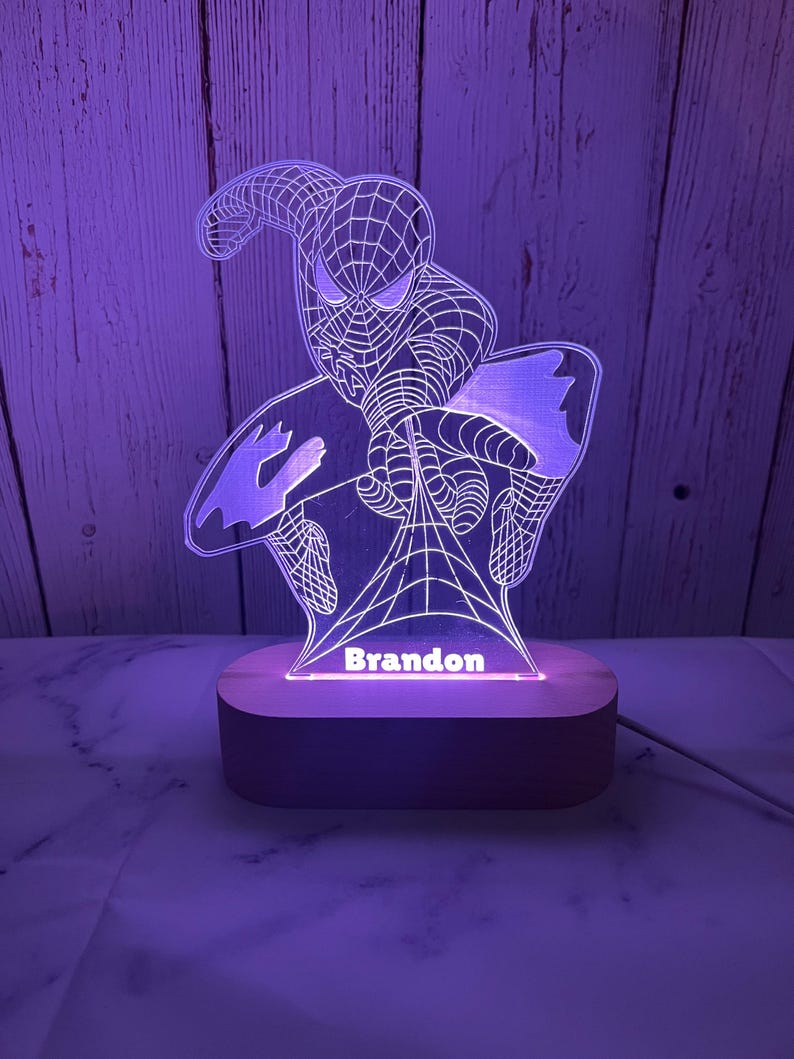 May include: A white and purple night light with a Spiderman design and the name "Brandon" on the base.