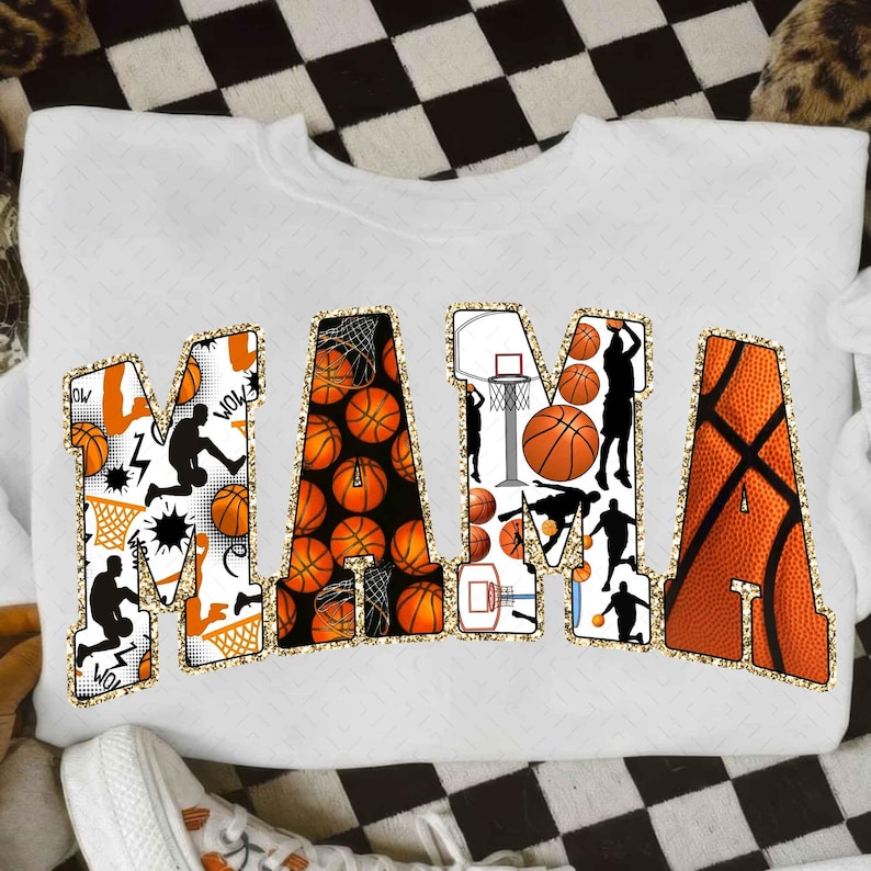 Puede incluir: Sudadera blanca con la palabra "MAMA" en letras grandes. Las letras est&aacute;n decoradas con balones de baloncesto, aros de baloncesto y siluetas de jugadores. Las letras est&aacute;n delineadas con purpurina dorada.