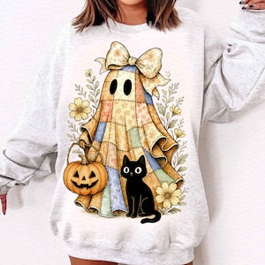 Może przedstawiać: Jasnoszara bluza z motywem Halloween. Projekt przedstawia patchworkowego ducha z dużą kokardą, czarnego kota, dynię i kwiatowe akcenty. Grafika jest w stylu akwareli.