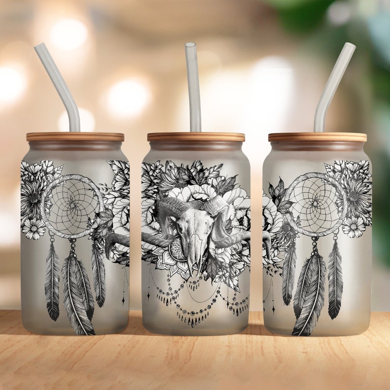 May include: Three frosted glass tumblers with bamboo lids and clear straws. Each tumbler features a different black and white design with a dreamcatcher, feathers, flowers, and a skull.