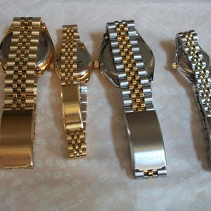 May include: Four gold and silver wristwatches with metal bands. The watches have different sizes and styles. The bands are all different styles and have the word "WINSTON" engraved on the clasp.