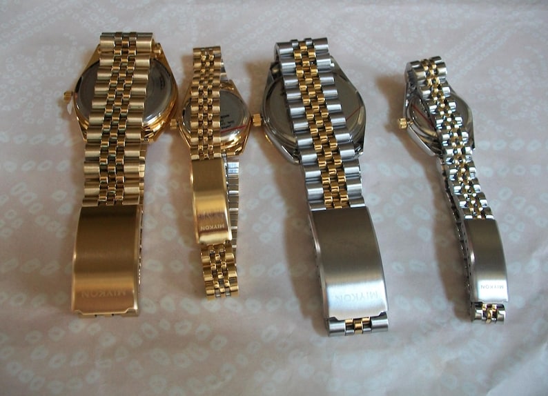 May include: Four gold and silver wristwatches with metal bands. The watches have different sizes and styles. The bands are all different styles and have the word "WINSTON" engraved on the clasp.