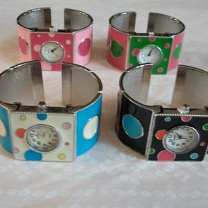 May include: Four silver bangle bracelets with colorful enamel and polka dot designs. Each bracelet features a square watch face with a white background and black hands.