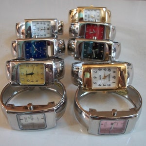 May include: A set of ten silver bangle watches with different colored faces. The watches have square faces with Roman numeral markings. The faces are white, yellow, blue, black, red, and pink.