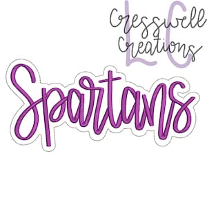 Könnte beinhalten: Ein lila gestickter Aufnäher mit dem Wort "Spartans" in Schreibschrift. Der Aufnäher hat einen weißen Umriss mit einem gepunkteten Rand. Der Text "cresswell creations" steht über dem Wort "Spartans".