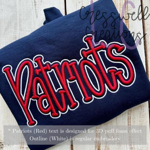 May include: Navy blue sweatshirt with the word "Patriots" embroidered in red with a white outline. The text is designed for a 3D puff foam effect. The sweatshirt is folded and displayed on a wooden surface.