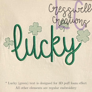 May include: Green embroidered design of the word "lucky" with four shamrock designs. The word "lucky" is designed for a 3D puff foam effect.  The shamrocks are regular embroidery.