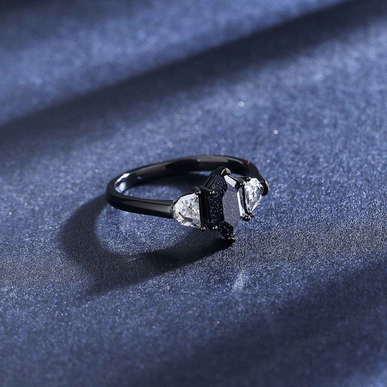 May include: A black ring with a large black gemstone surrounded by three smaller white gemstones.