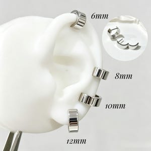 May include: A set of four silver-toned hoop earrings displayed on a white ear model. The hoops are labelled with sizes 6mm, 8mm, 10mm, and 12mm. An inset circle shows the earrings detached, highlighting their hinged closure mechanism and polished finish.