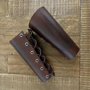 Pair of handmade brown leather bracers with lace-up design. Perfect for cosplay, Renaissance fairs, medieval reenactment, and SCA events. Crafted from real leather, offering a durable and stylish accessory for role-playing.