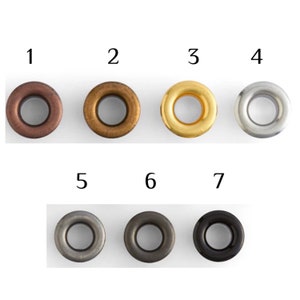 Seven metal eyelets in different finishes labeled 1 to 7: copper, antique brass, gold, silver, gunmetal, dark silver, and black. Displayed in two rows on a white background, ideal for leathercraft, sewing, or DIY projects.