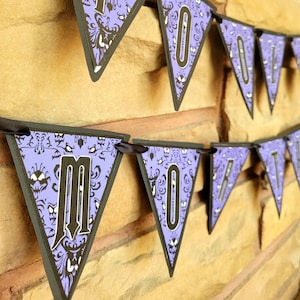 May include: Purple and black Halloween banner with a spooky mansion pattern and the word "Haunted" in black letters.