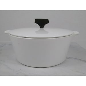 May include: White enameled cast iron Dutch oven with a black handle on the lid. The pot has two side handles and a rounded shape. A classic kitchen cookware item.