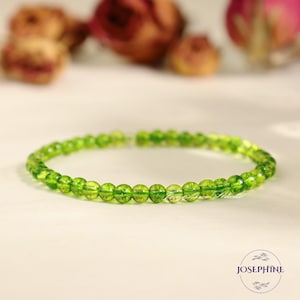 May include: A green gemstone bracelet made of small, round beads. The bracelet is delicate and has a simple design.