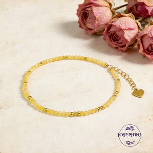 May include: A delicate bracelet featuring small, faceted yellow beads interspersed with smooth gold-toned metal spheres. The bracelet includes a gold-toned chain extender finished with a small, flat heart-shaped charm.