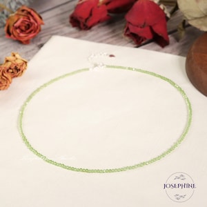 May include: A delicate green crystal beaded necklace with a silver clasp. The necklace is on a white background.