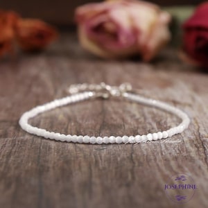 Puede incluir: Un delicado brazalete de cuentas blancas con cierre plateado. El brazalete está hecho de pequeñas cuentas redondas y es perfecto para superponer con otros brazaletes.