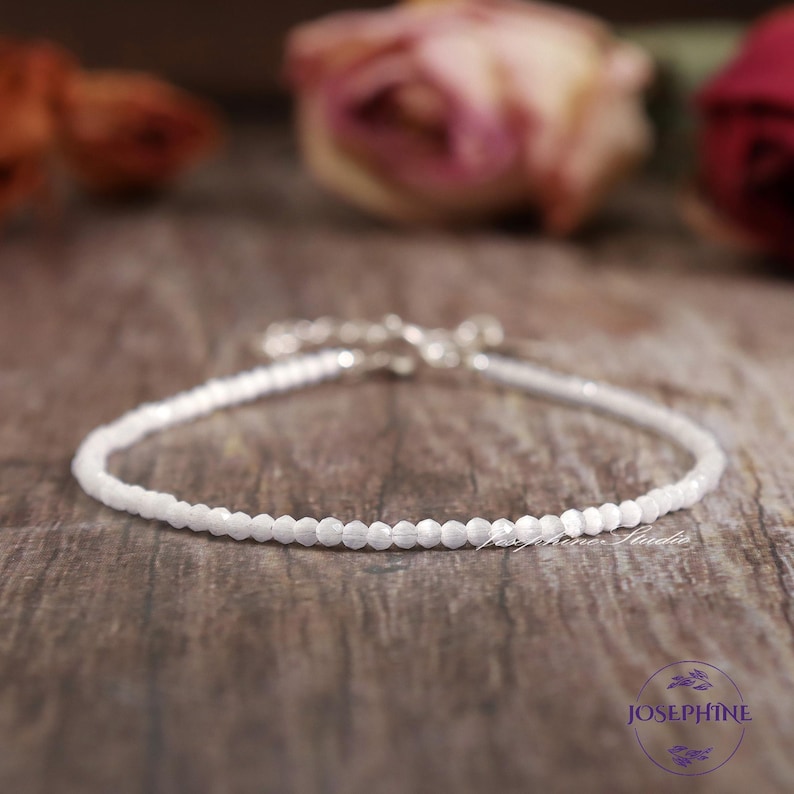 May include: A delicate white beaded bracelet with a silver clasp. The bracelet is made of small, round beads and is perfect for layering with other bracelets.