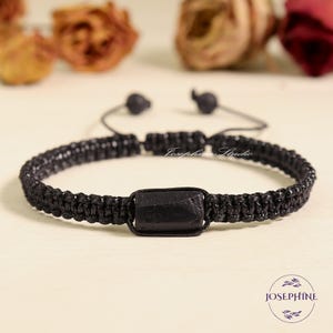May include: Black macrame bracelet with a rectangular black stone centerpiece. The bracelet is adjustable with a sliding knot closure. The image includes the text "Josephine Studio" and the "Josephine" logo.