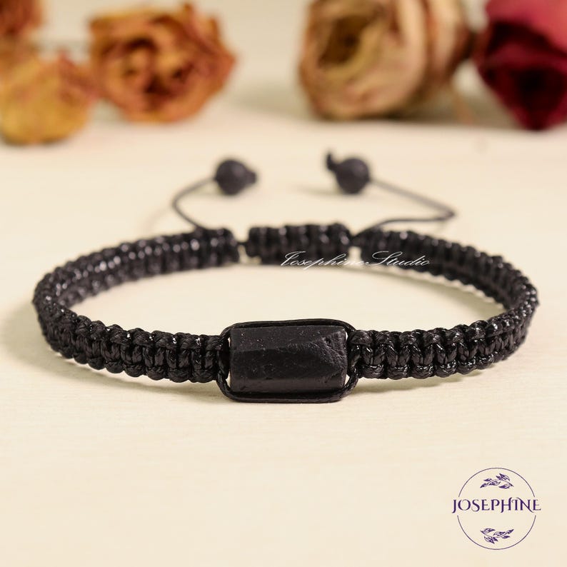 May include: Black macrame bracelet with a rectangular black stone centerpiece. The bracelet is adjustable with a sliding knot closure. The image includes the text "Josephine Studio" and the "Josephine" logo.