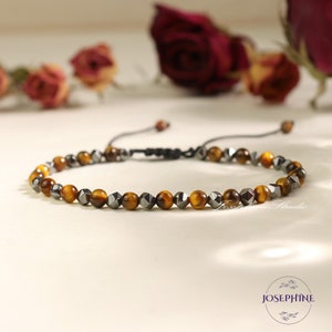 May include: A brown and black beaded bracelet with a sliding knot closure. The beads are made of tiger's eye and hematite.