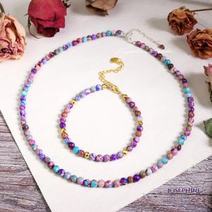 以下が含まれることがあります： カラフルな模様のビーズで作られた2つのネックレスのセット。ネックレスは長く、シルバーの留め具が付いています。ブレスレットは短く、ゴールドの留め具が付いています。どちらも小さな丸いビーズで作られています。