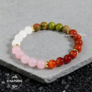 Op de afbeelding: Een kralenarmband met verschillende edelstenen. De armband bevat witte, roze, groene en rood-oranje kralen, gescheiden door goudkleurige afstandhouders. De armband wordt gepresenteerd op een grijze ondergrond. De merknaam "Josephine Studio" is zichtbaar.