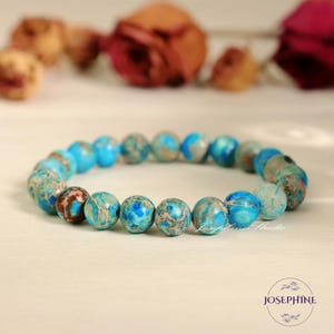 May include: A blue and brown patterned beaded bracelet. The beads are round and have a marbled appearance.
