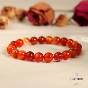 May include: A red carnelian gemstone bracelet with round beads. The bracelet is made of natural stones and is a beautiful accessory for any occasion.