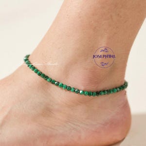 May include: A green beaded anklet made of small, faceted beads. The anklet is worn around the ankle. The image also includes the text "Josephine" in a circular logo.