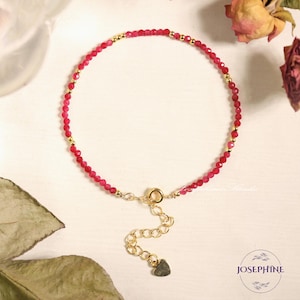 Pu&ograve; includere: Un braccialetto delicato realizzato con piccole perle di pietre preziose rosse e dettagli dorati. Il braccialetto ha una chiusura a forma di cuore.
