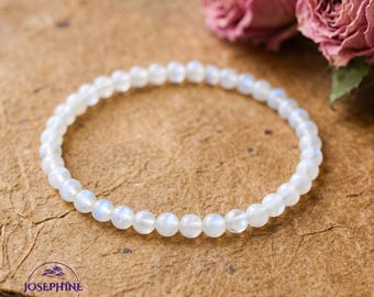 May include: A delicate white beaded bracelet with a subtle iridescent sheen. The bracelet is composed of small, round beads and is displayed on a textured, brown surface. The word "JOSEPHINE" is printed on the bottom left of the image.