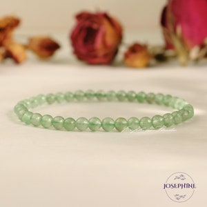 May include: A green gemstone beaded bracelet with a simple design. The bracelet is made of small, round beads that are strung together on a clear elastic cord.