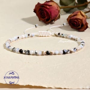 May include: Adjustable beaded bracelet featuring a mix of white, black, and gray faceted beads. The bracelet has a macrame closure and is displayed with dried roses. The text "Josephine Studio" is visible.
