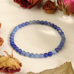 May include: A blue gemstone bracelet with graduated beads, ranging from light blue to dark blue.