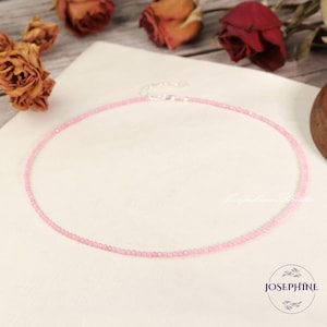May include: A delicate pink beaded necklace with a silver clasp. The necklace is made of small, round beads and is perfect for layering with other necklaces.