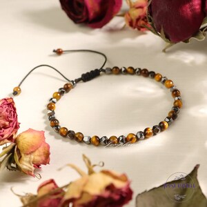 May include: A brown and black beaded bracelet with a black cord closure. The beads are faceted and have a metallic sheen.