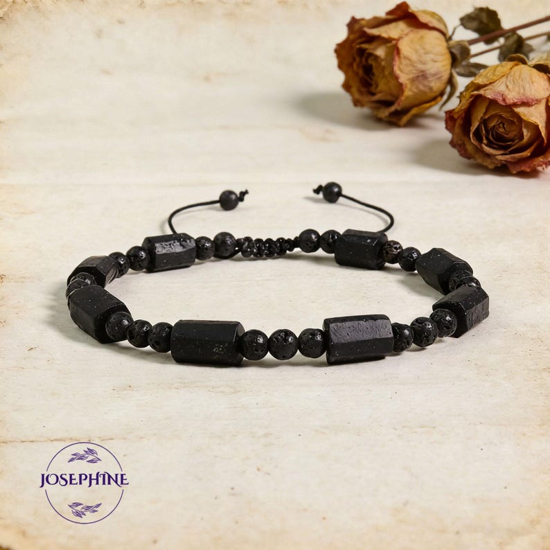 May include: Black beaded bracelet featuring rectangular and round beads. The bracelet has a sliding knot closure for adjustable sizing. The beads are a mix of smooth and textured surfaces. The bracelet is displayed on a neutral background.