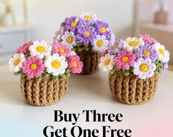 May include: Three crocheted flower arrangements in brown textured pots. Each pot contains a cluster of white, pink, and purple daisies with yellow centers and green leaves. The text "Buy Three Get One Free" is printed in black at the bottom.