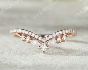 May include: A delicate rose gold wedding band with a V-shaped design. The band is adorned with small, sparkling diamonds.