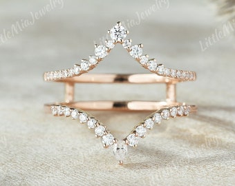 Puede incluir: Un anillo de oro rosa con un delicado diseño en forma de V. El anillo está engastado con pequeños diamantes brillantes.