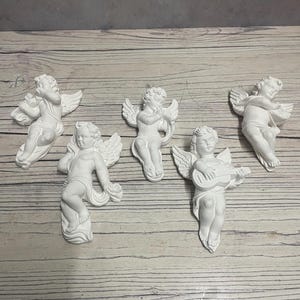 May include: Five white plaster cherub figurines, each playing a different musical instrument. The cherubs are posed in a flying position with wings outstretched.