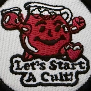 May include: Embroidered patch featuring a smiling, red cartoon character with a pitcher-shaped body. The patch has the text "Let's Start A Cult!" in black lettering on a white background, framed by a black border.
