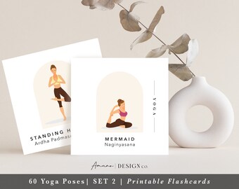 May include: Two printable yoga pose flashcards with illustrations of women in the Ardha Padmasana and Naginyasana poses. The text on the cards reads "Standing Half Lotus", "Ardha Padmasana", "Mermaid", "Naginyasana", "Yoga", "Amano DESIGN co.", "60 Yoga Poses", "SET 2", and "Printable Flashcards".