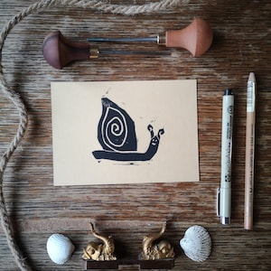 Linoldruck Postkarte mit maritimen Kindermotiv süße Strandschnecke auf Kraftpapier hellbraun, handgefertigte Karte Einladung Geburtstag