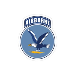 Può includere: Un adesivo raffigurante un'aquila stilizzata con le ali spiegate, su un cerchio azzurro. L'aquila è blu scuro con dettagli bianchi e un becco giallo. La parola "AIRBORNE" è visualizzata sopra l'aquila.