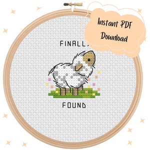 May include: A cross-stitch pattern featuring a white sheep with black spots, surrounded by pink flowers. The text "FINALLY FOUND" is written above and below the sheep.