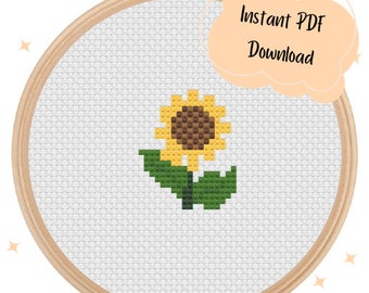May include: A cross-stitch pattern of a sunflower with green leaves. The pattern is displayed in a wooden embroidery hoop.